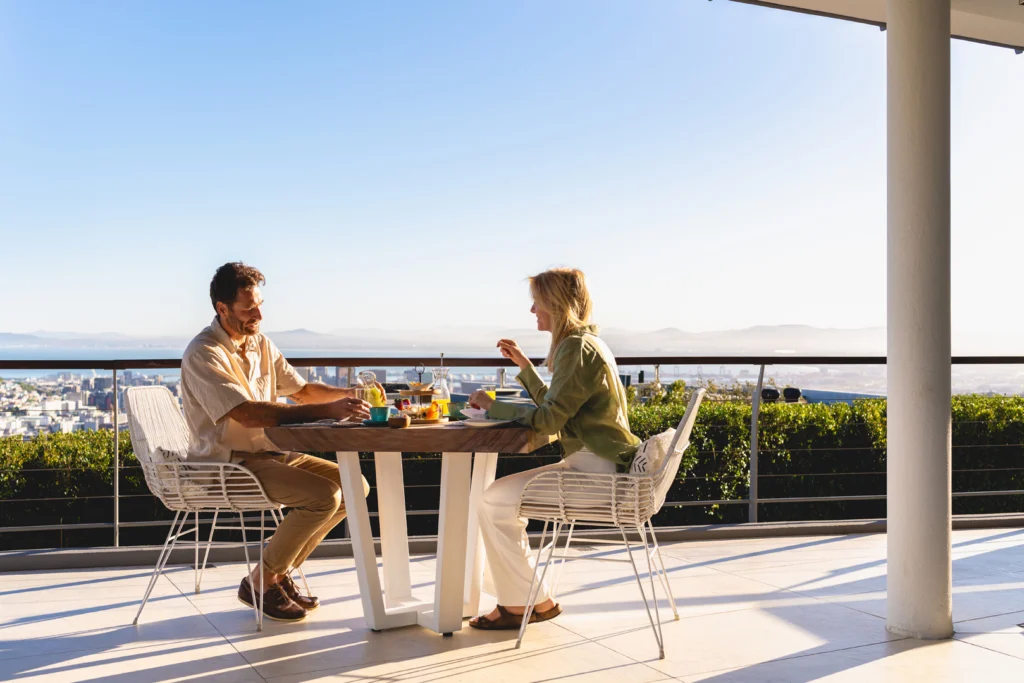 A couple sharing a meal at a small table with a scenic, blue sky backdrop.