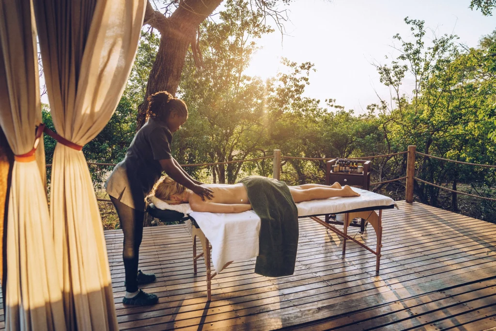 A guest enjoys a massage at the Atzaró Okavango spa, bathed in warm golden sunlight and surrounded by natural beauty.
