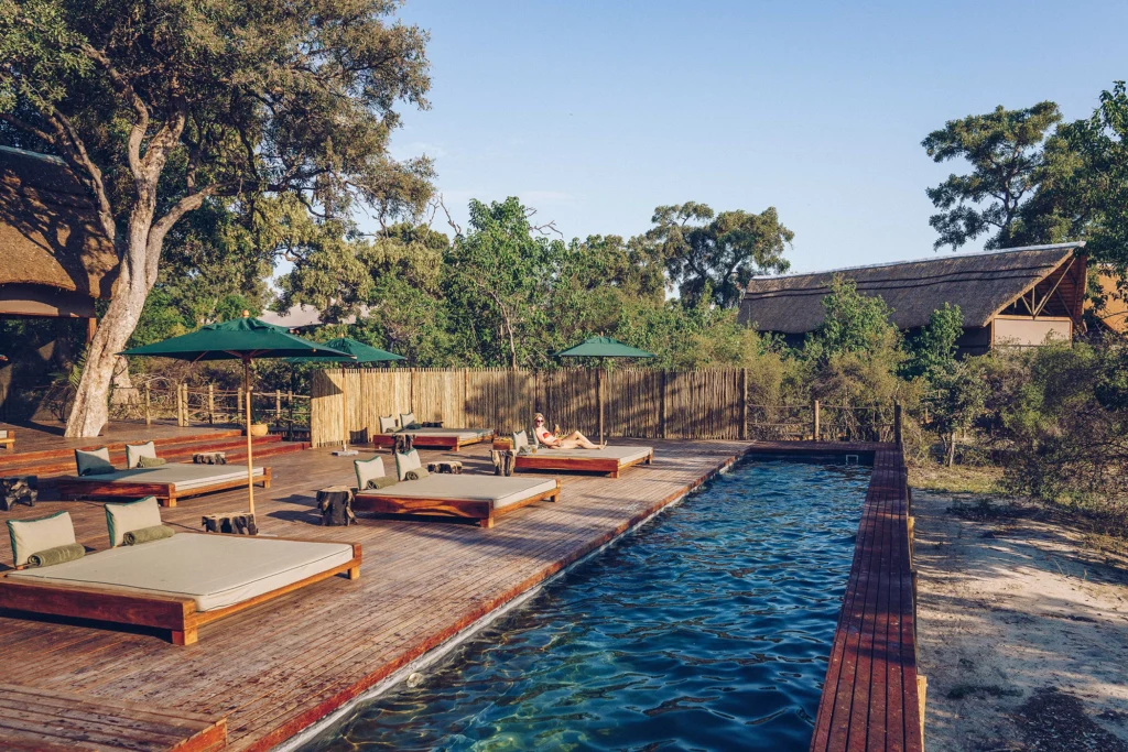Luxurious pool and daybed deck at Atzaró Okavango, bathed in sunlight with views of the surrounding wilderness.