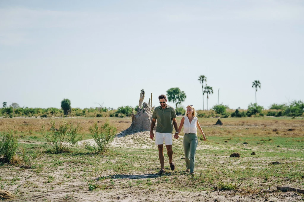 A couple on a guided walking safari through the Okavango Delta, surrounded by open wilderness and led by an expert guide.
