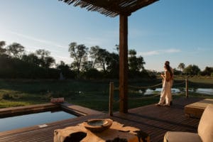 Couple enjoying sunset views from a wooden safari deck at Atzaró Okavango Camp in the Okavango Delta, Botswana.