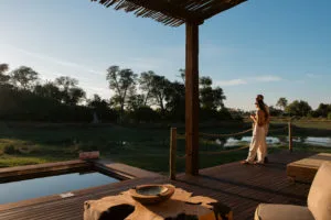 Couple enjoying sunset views from a wooden safari deck at Atzaró Okavango Camp in the Okavango Delta, Botswana.