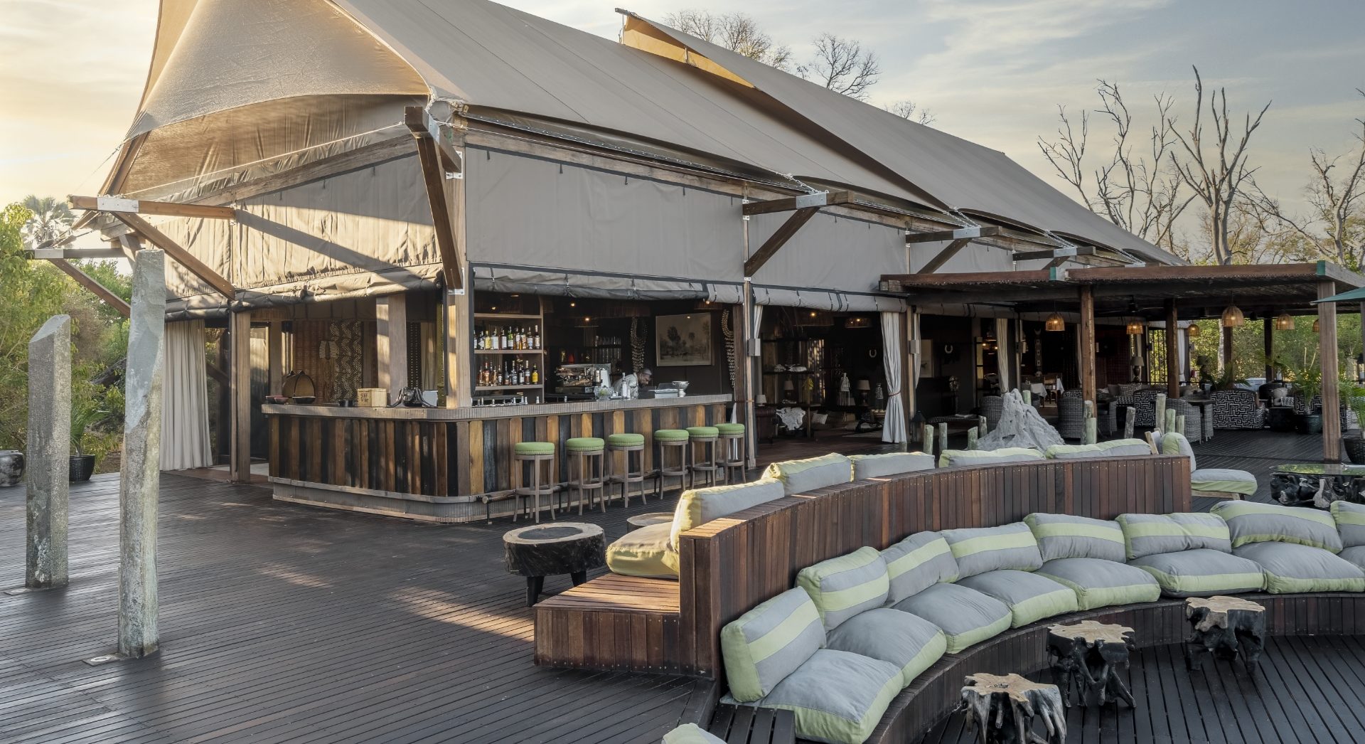 The main bar and expansive outdoor lounge deck at Atzaró Okavango Camp in the Okavango Delta, Botswana, featuring contemporary safari design and comfortable sunken seating.