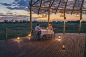 A couple dining in the Ancestral Boma in Atzaró Okavango Camp.