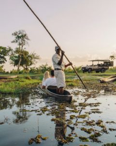 Guide steering a mokoro canoe through the Okavango Delta wetlands in Botswana during a luxury safari adventure.