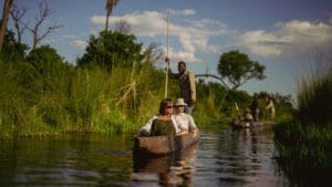 Couple on a mokoro safari gliding along a channel in the Okavango Delta, Botswana