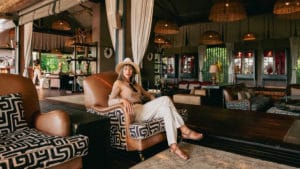 Guest in comfortable beige clothing sitting at the entrance of Atzaró Okavango Camp, a safari packing list example